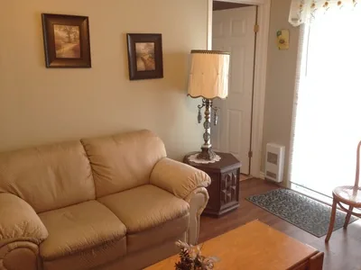 Salon intérieur avec canapé beige et lampe près d’une fenêtre.