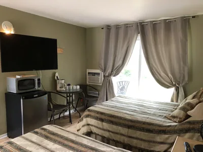 Vue intérieure d’une chambre de motel comprenant deux lits et un petit réfrigérateur.
