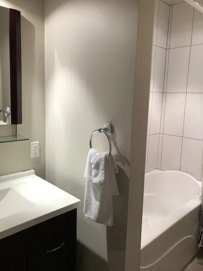 Salle de bain montrant un lavabo blanc, une serviette et une baignoire.